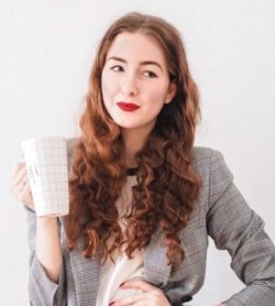 woman in gray cardigan holding white ceramic mug